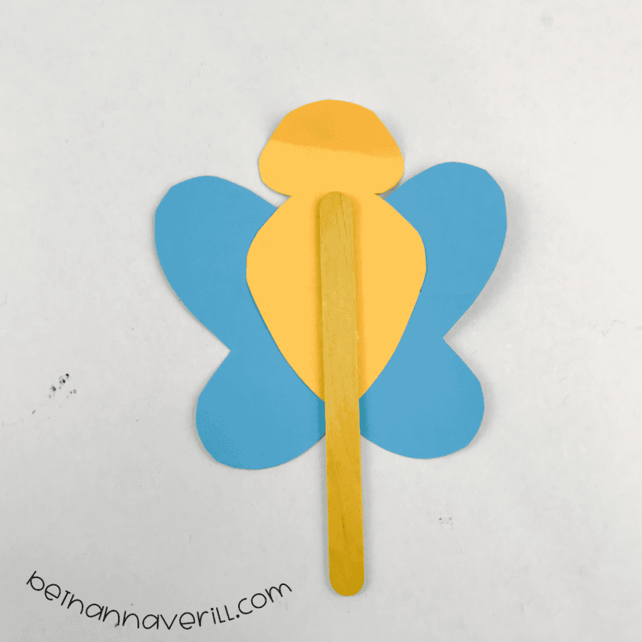 Blue paper wings and a yellow body attached to a popsicle stick