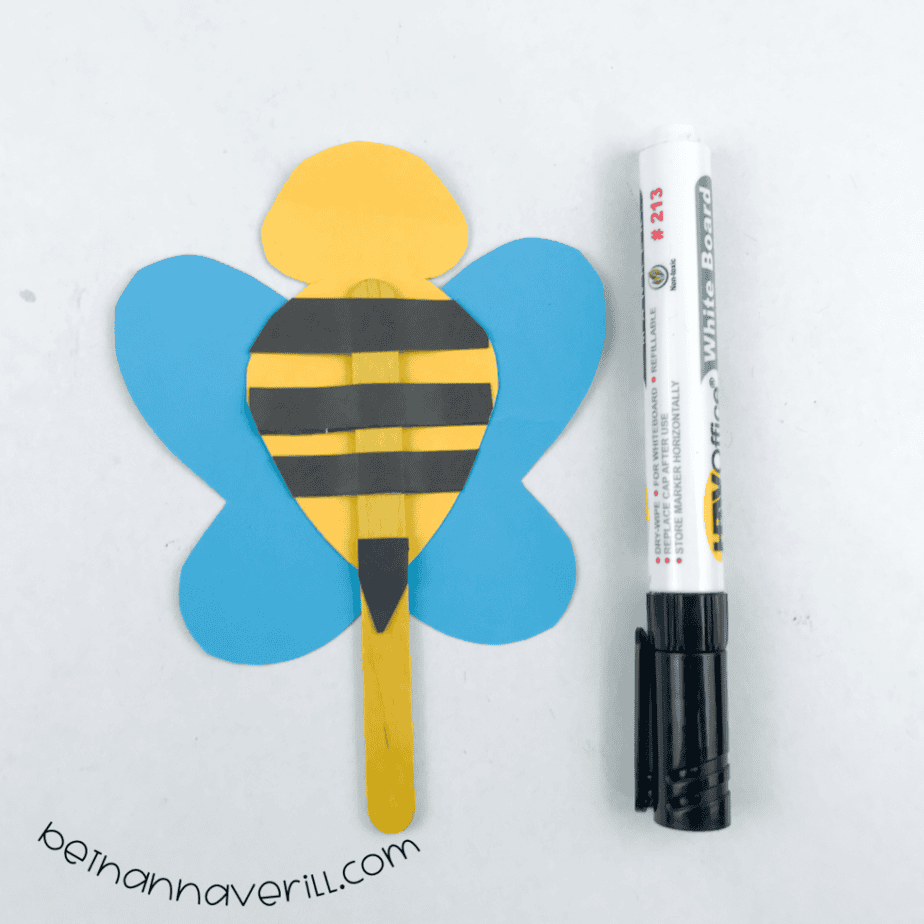 Bee puppet with black stripes and a stinger next to a marker