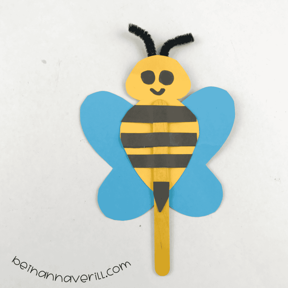 Finished popsicle stick bee puppet with a smile and fuzzy wire antennae