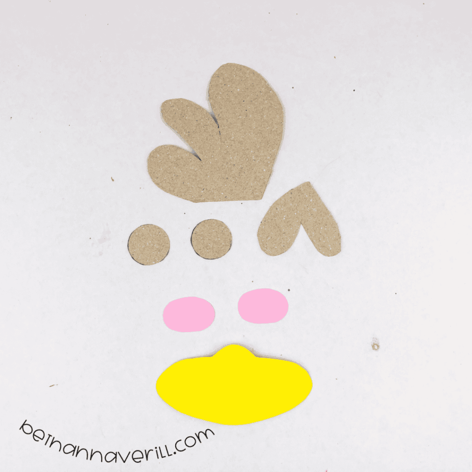 Comb and wattle shapes cut from thin cardboard with a yellow beak and pink cheeks