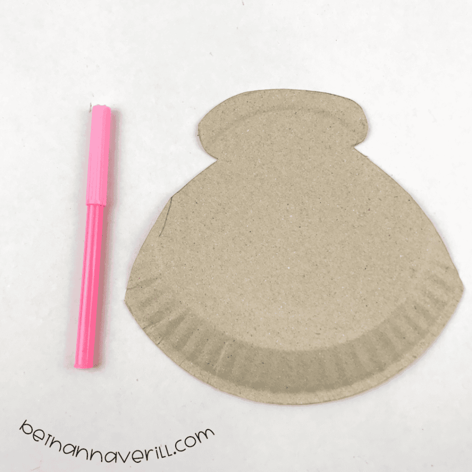 Clam shell shape cut from the bottom of a paper plate next to a pink pen