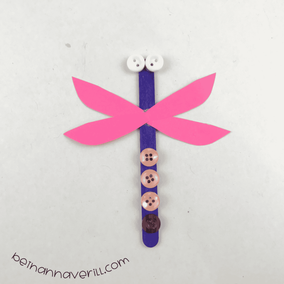 Finished craft stick dragonfly puppet with pink wings and button eyes