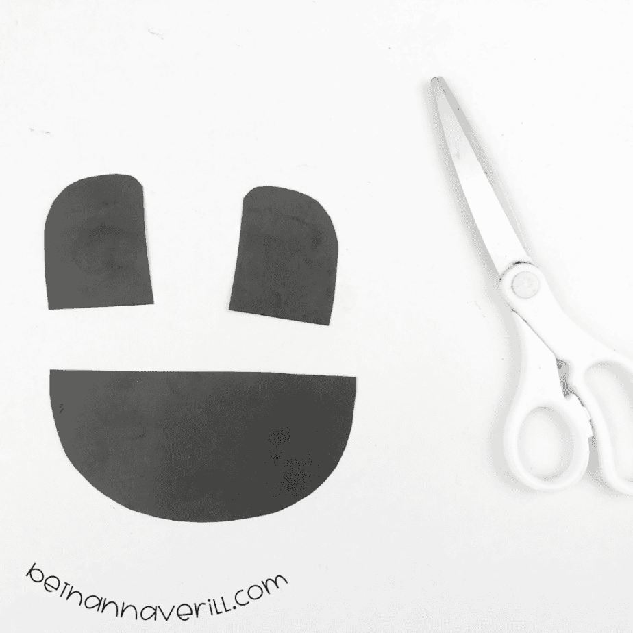 Two small black arcs and a black half circle cut from black paper