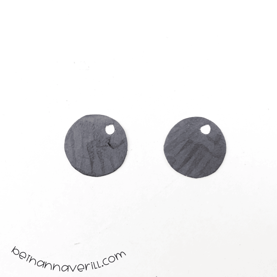 Two black paper eye circles with white dots