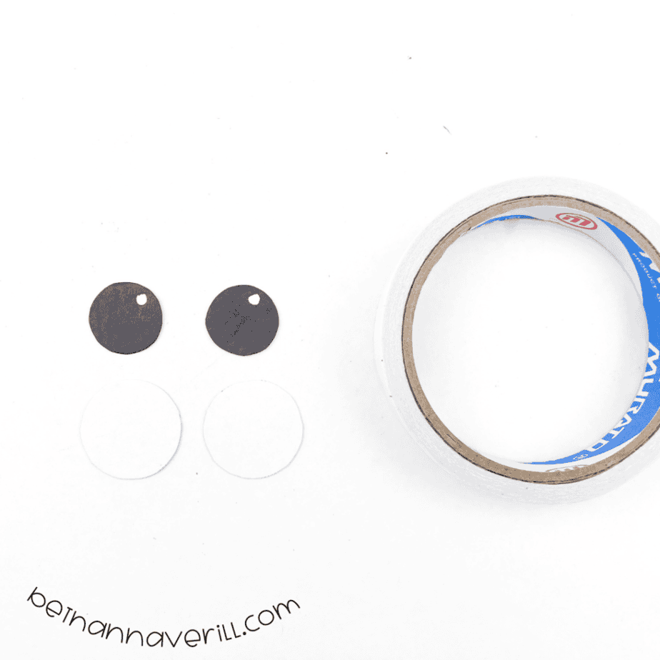 Black eyes glued onto white circles next to tape