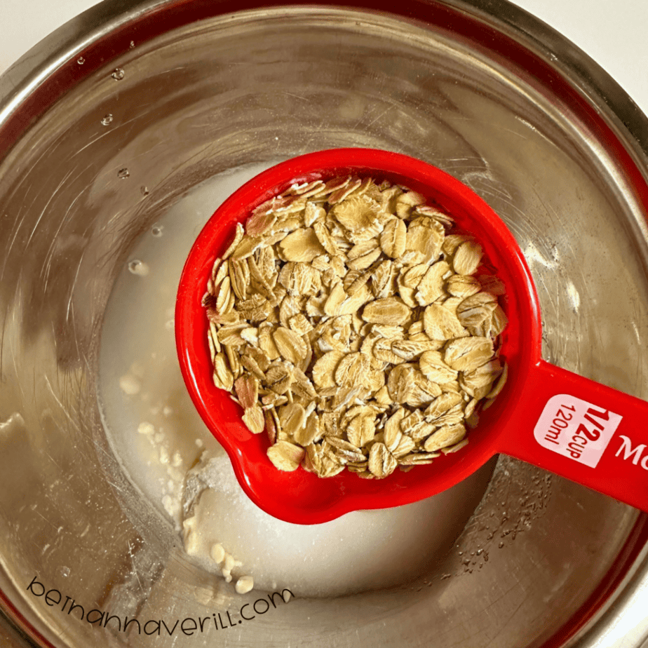 Measuring cup of rolled oats added to the playdough mixture