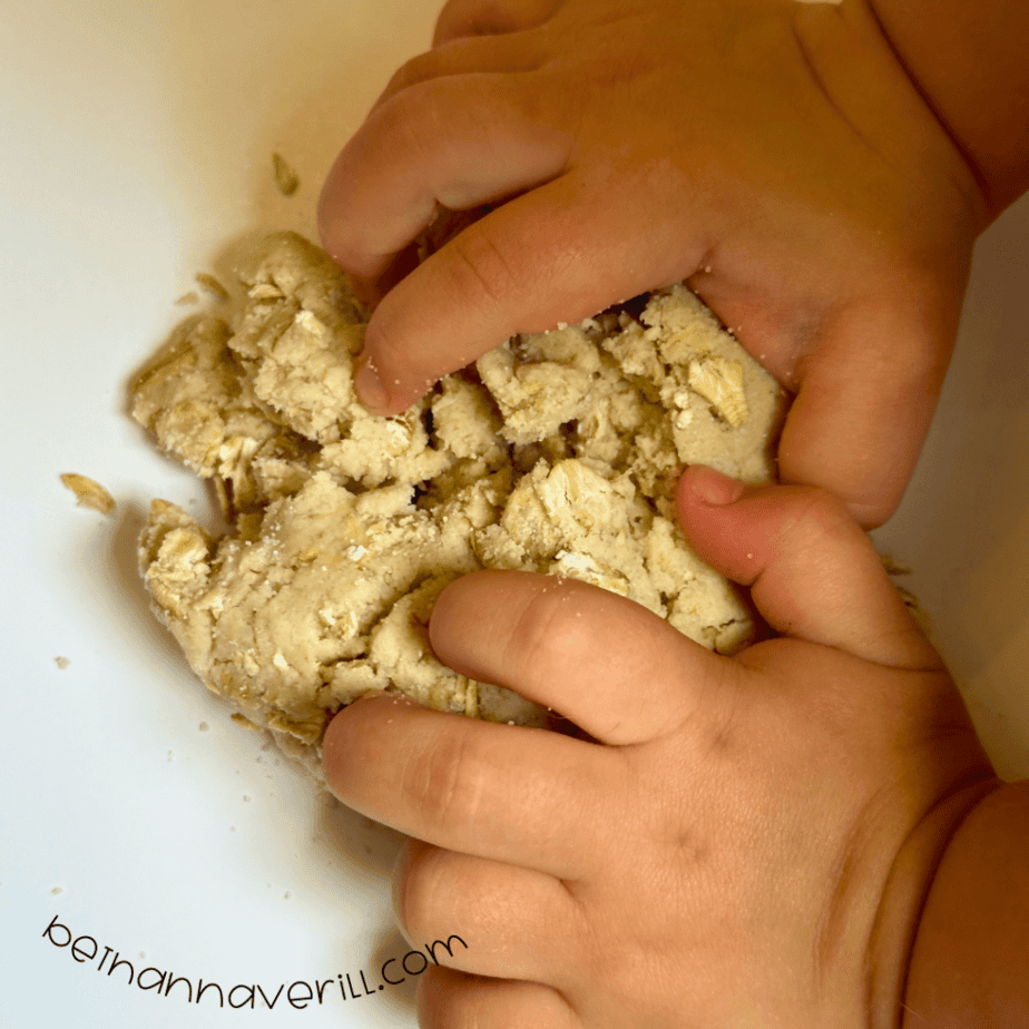 Child’s hands squeezing bumpy homemade oatmeal playdough
