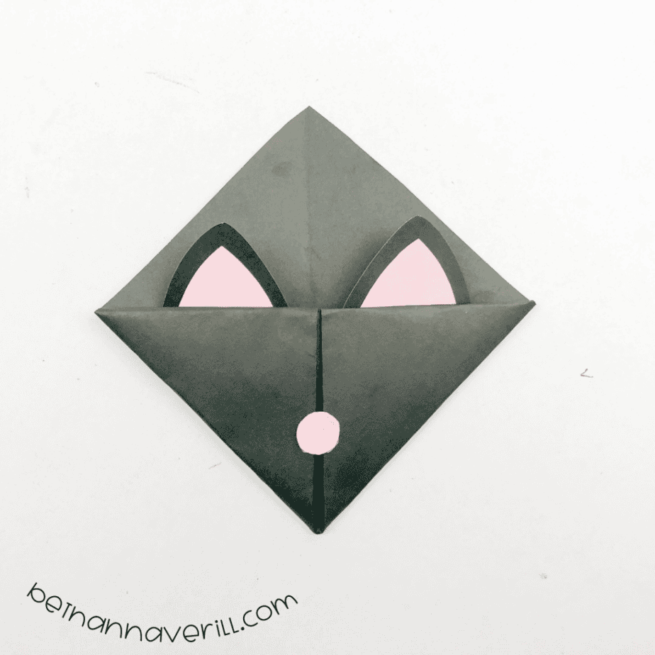 Black origami bookmark with cat ears and a pink nose attached