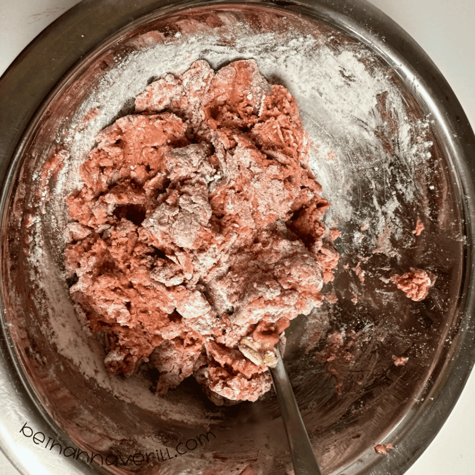 Red cinnamon applesauce playdough being mixed in a metal bowl