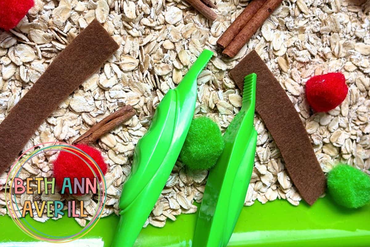 red and green pom poms on a base of oat for a sensory bin.