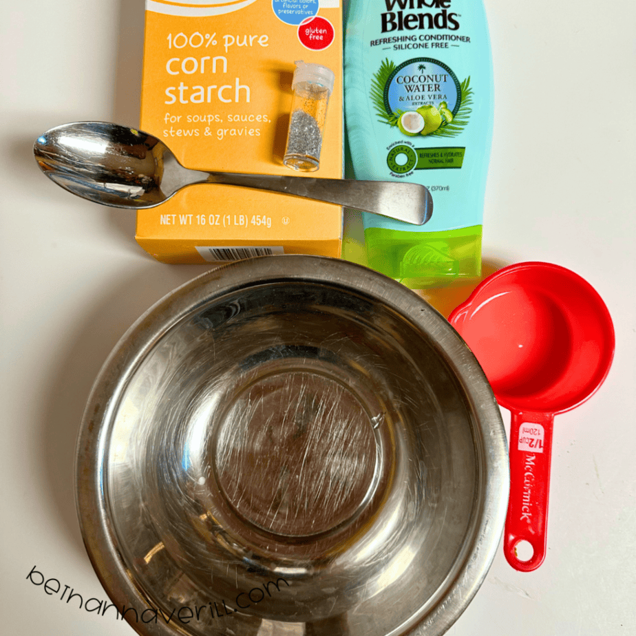 Snow dough supplies including cornstarch, white hair conditioner, a mixing bowl, measuring cup, and spoon