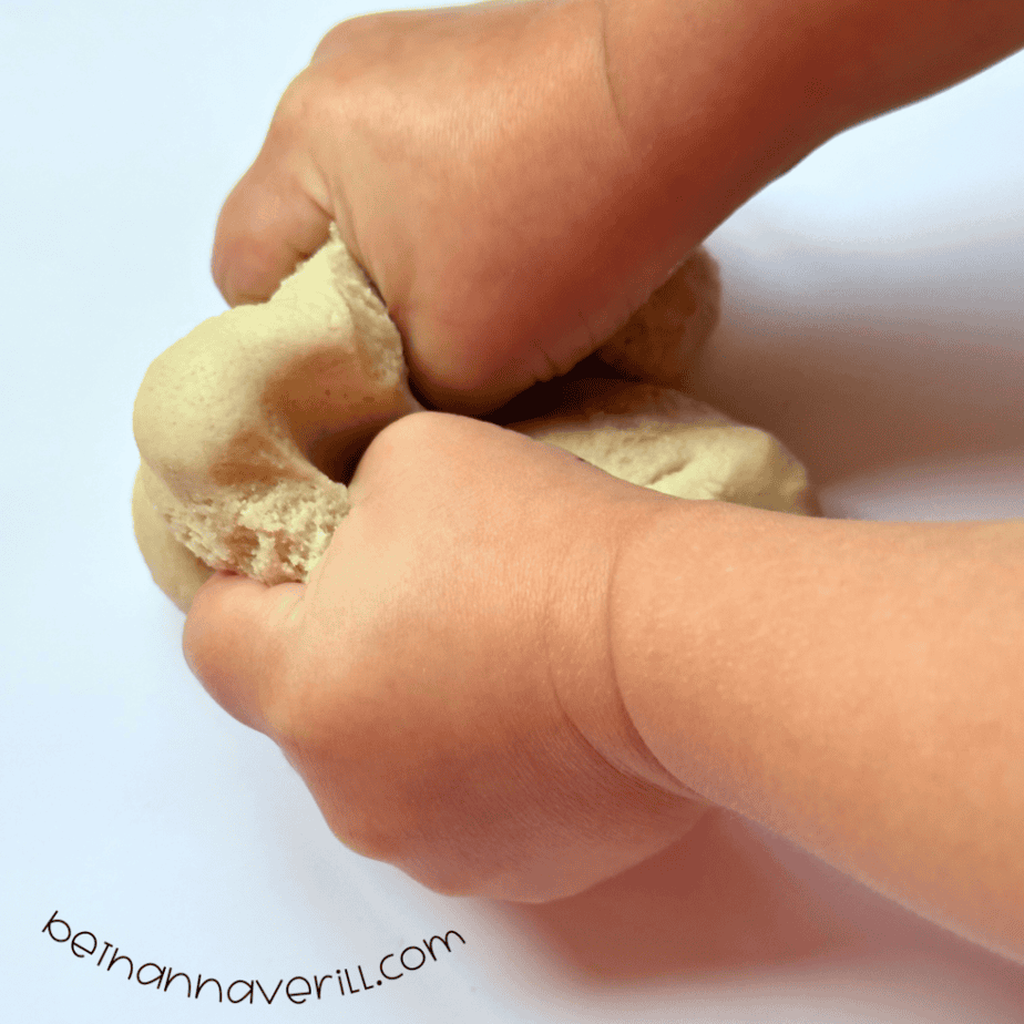 Child’s hands squeezing a ball of homemade vanilla playdough