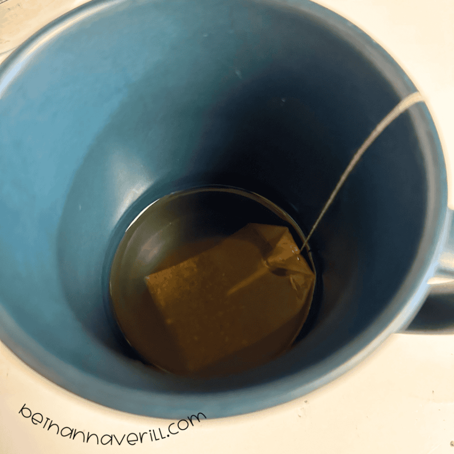Green tea bag steeping in a mug of hot water