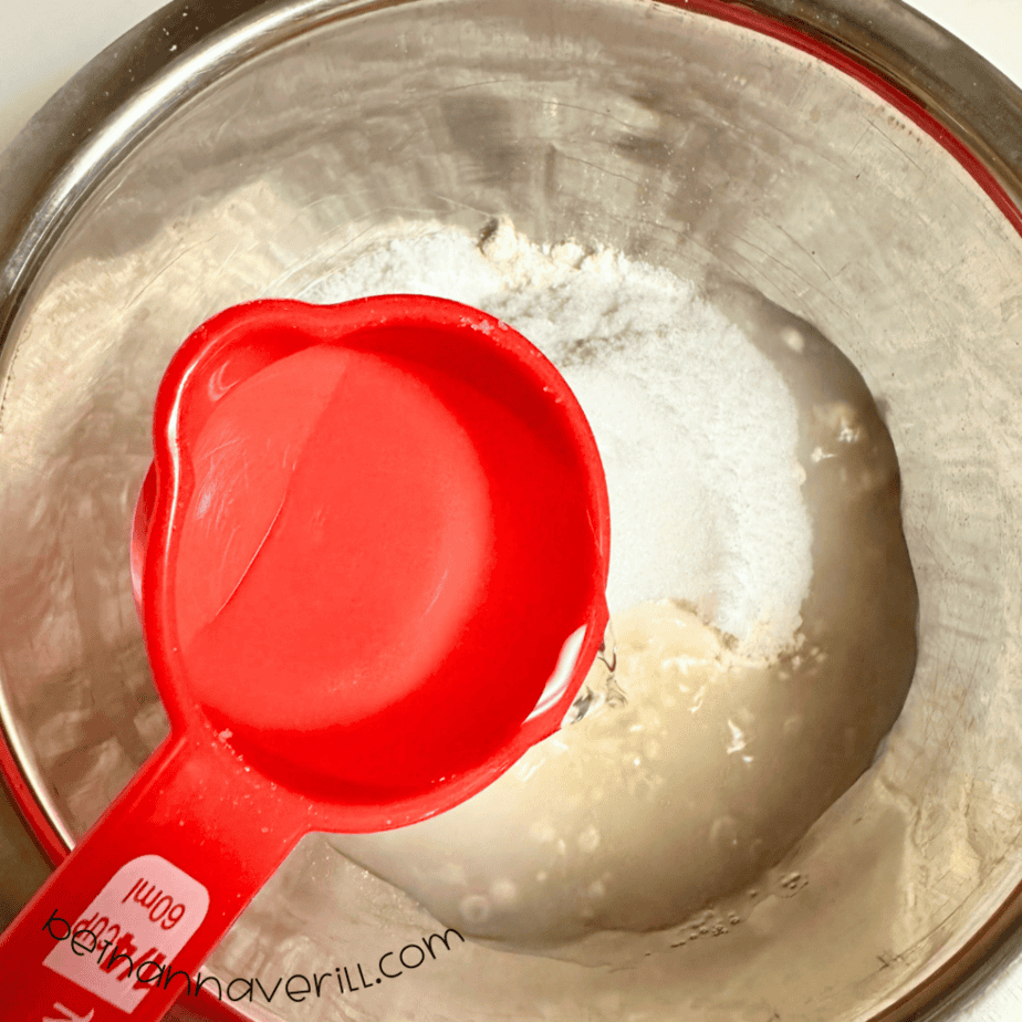 Water poured from a red measuring cup into the dry ingredients