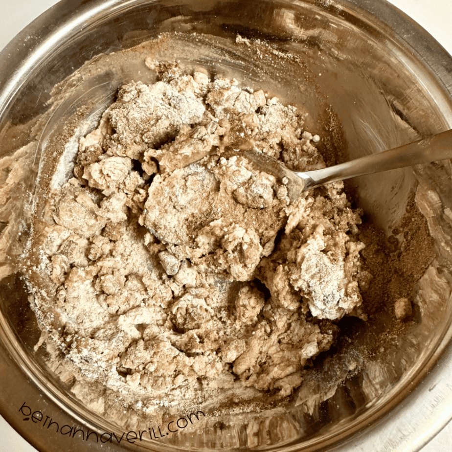 Crumbly hot cocoa playdough coming together in a metal mixing bowl