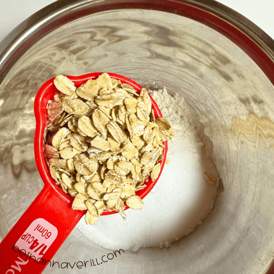 Measuring cup of rolled oats added to the flour and salt