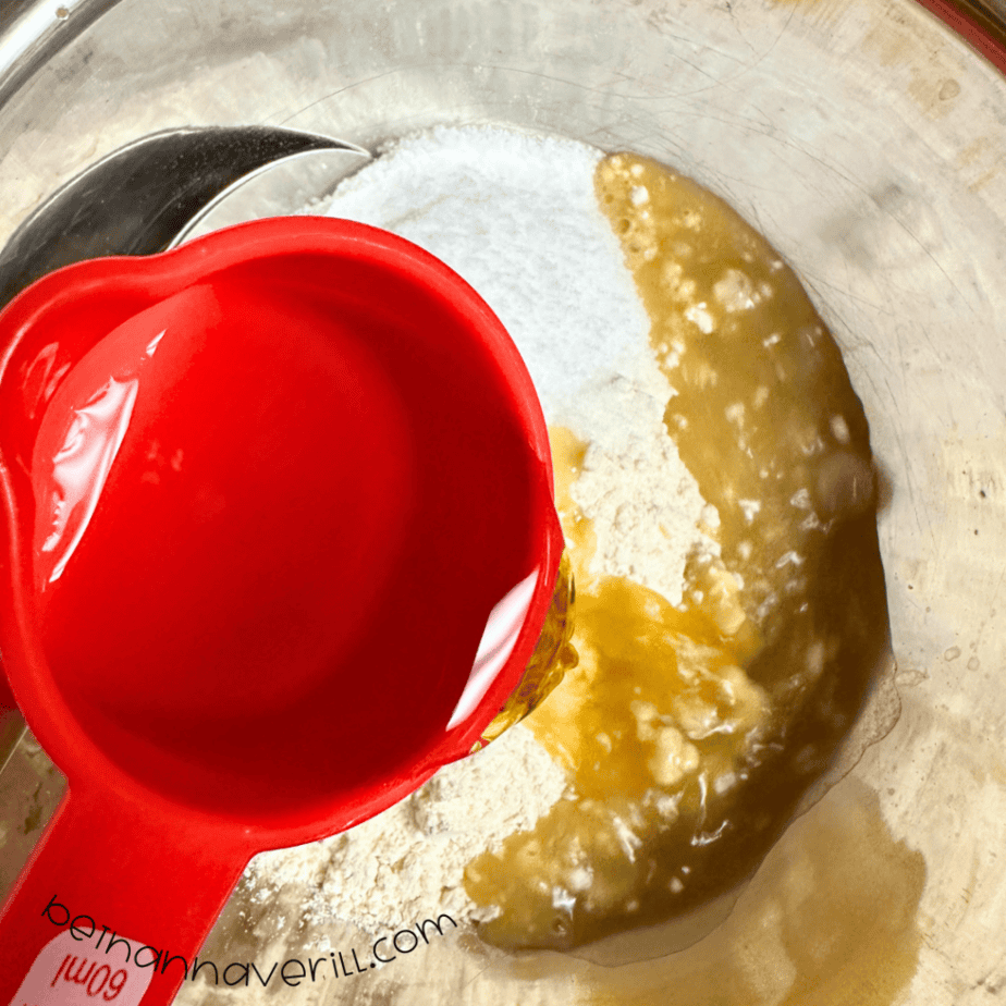Cooled peppermint tea poured from a red measuring cup into the playdough mixture