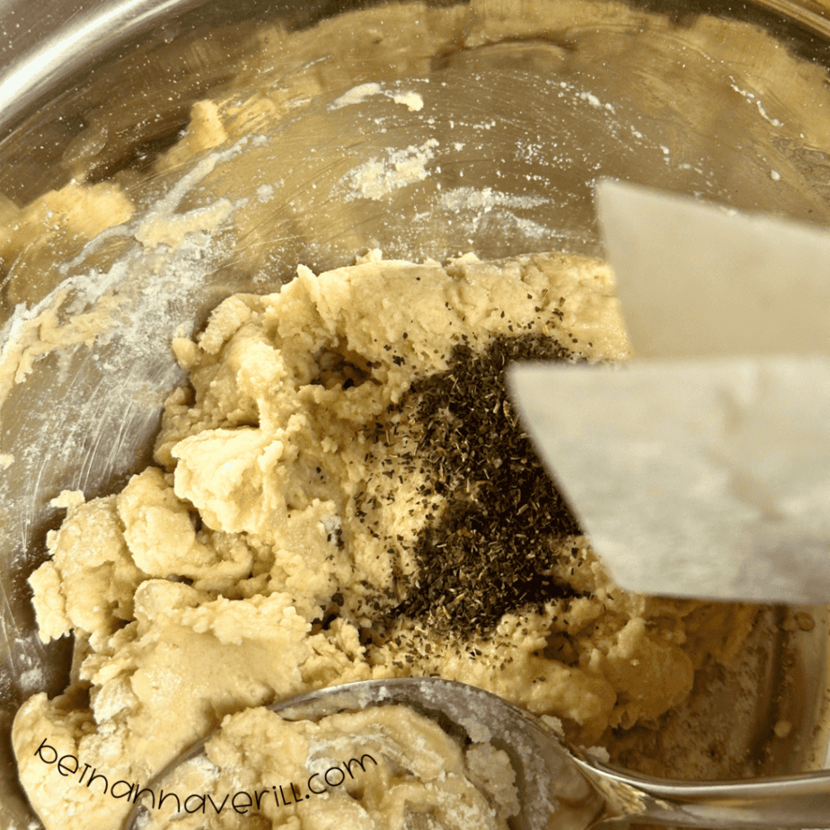 Peppermint tea leaves sprinkled over crumbly playdough in a mixing bowl
