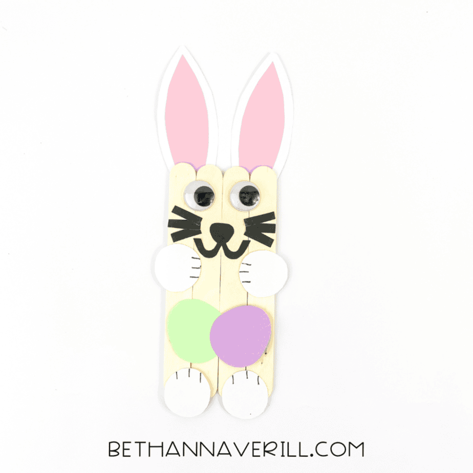 Finished popsicle stick bunny craft holding Easter eggs