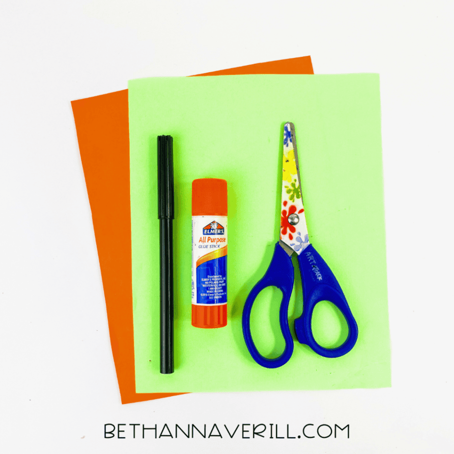 Paper carrot supplies: orange and green paper, glue stick, marker and scissors
