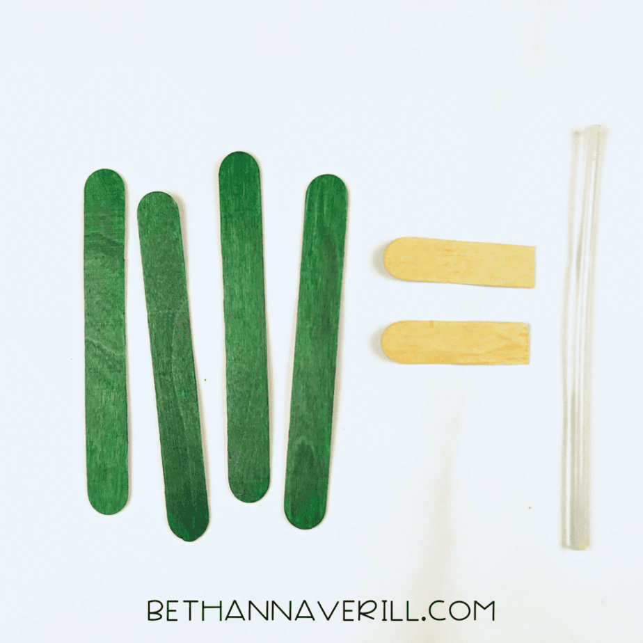 Green craft sticks next to an unpainted stick cut in half