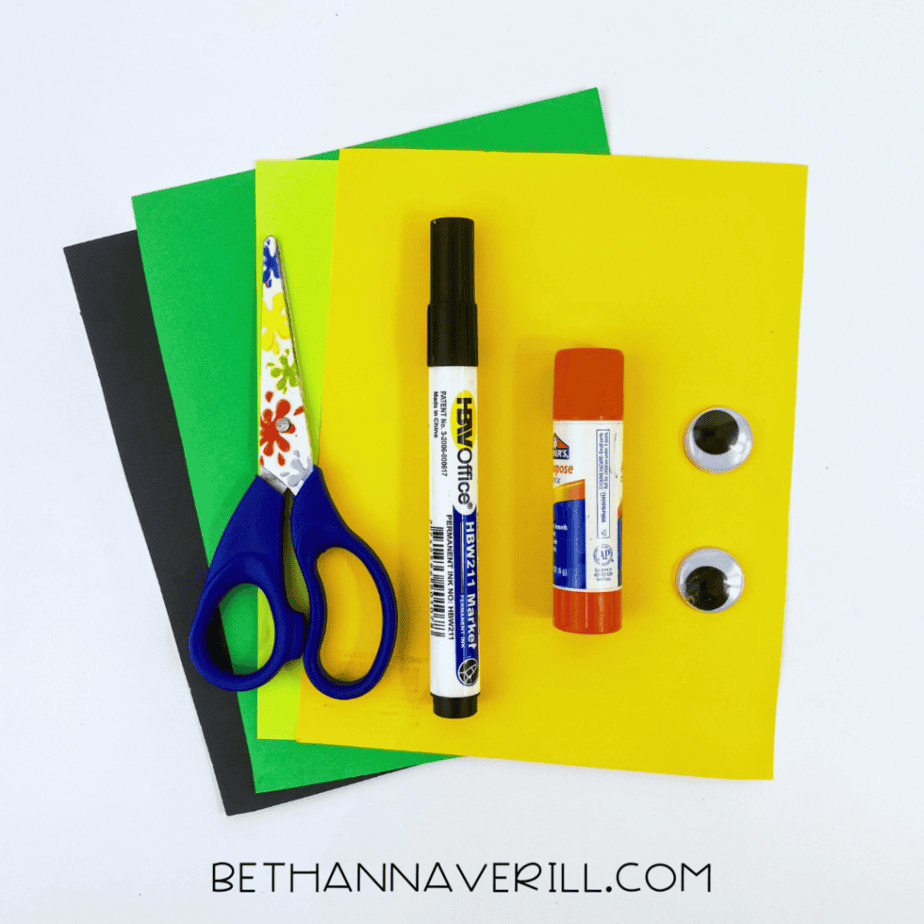 Shamrock craft supplies: green, yellow and black construction paper, scissors, marker, glue stick and googly eyes