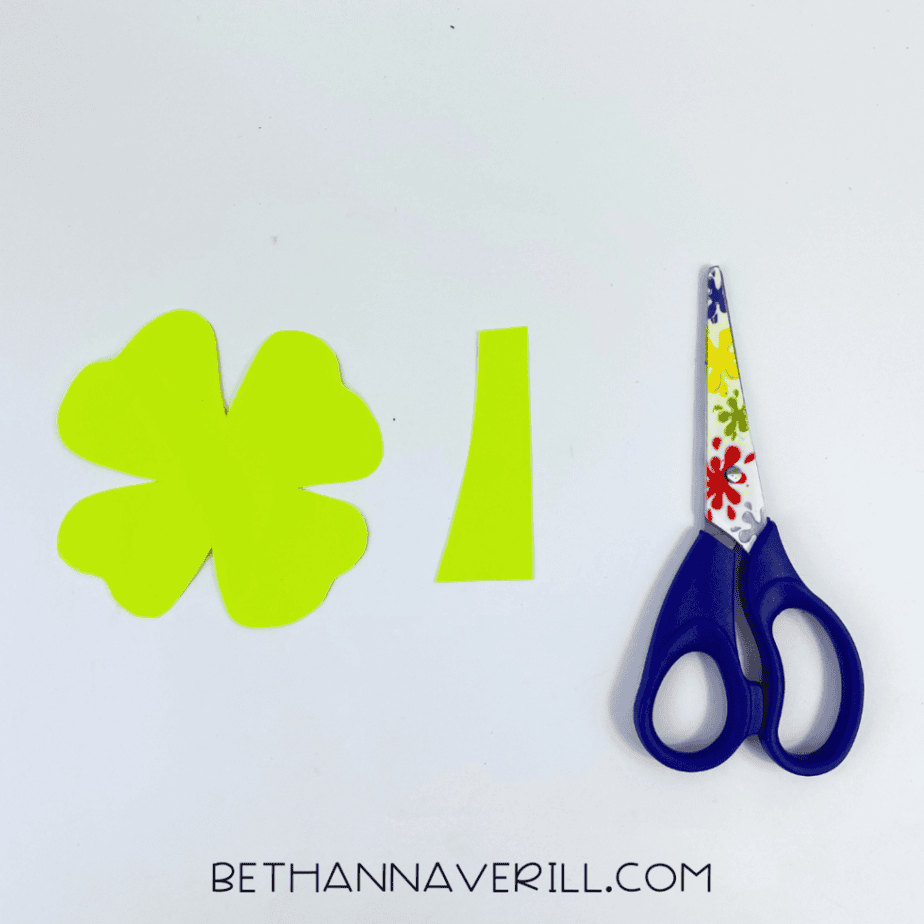 Light green paper shamrock and stem cut out next to scissors