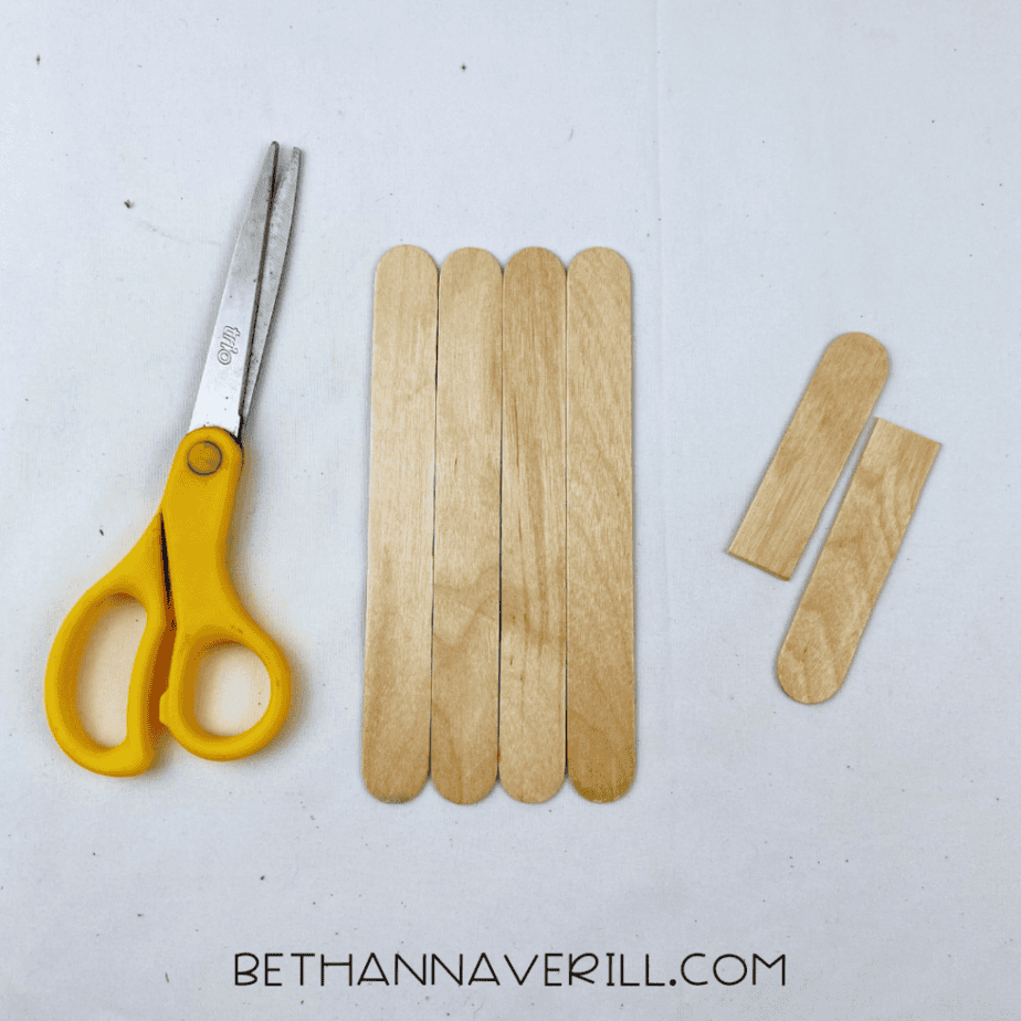 Four craft sticks next to a stick cut in half