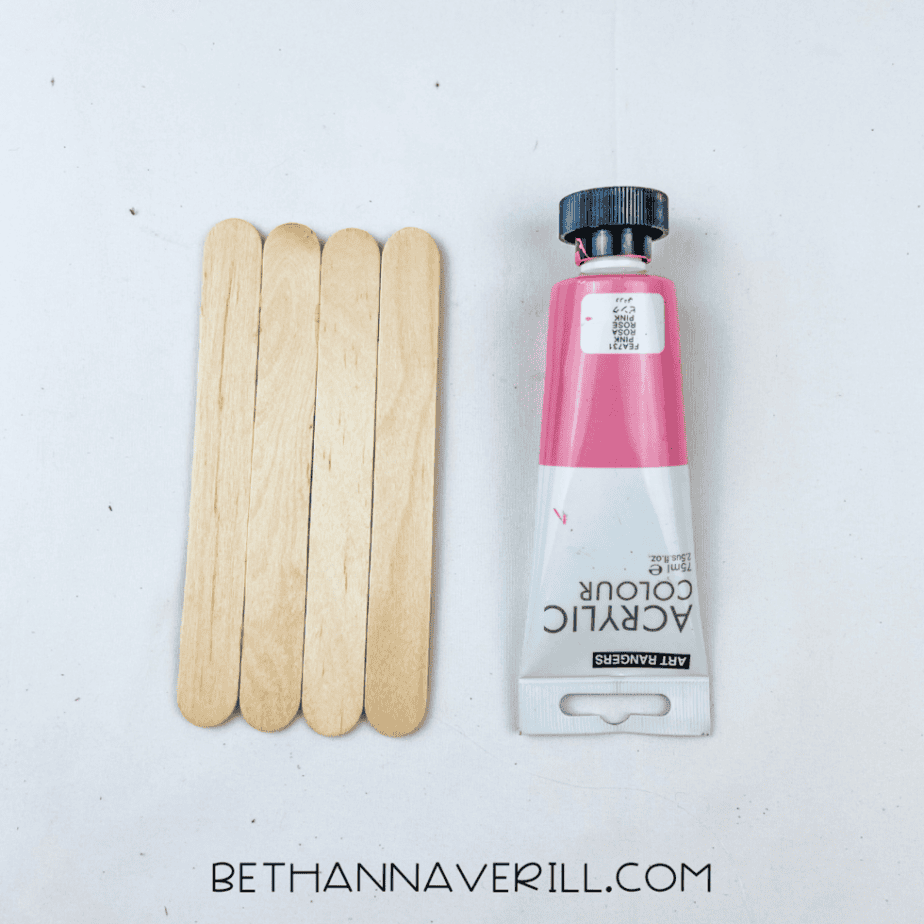 Craft sticks next to pink paint