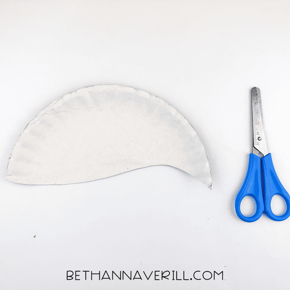 A paper plate cut in half, ready to become the flamingo's body.