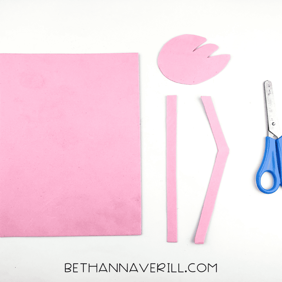 Pieces of pink paper cut into flamingo legs and a wing, ready for assembly.