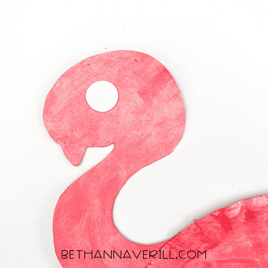 A white circle eye is glued onto the flamingo’s head.