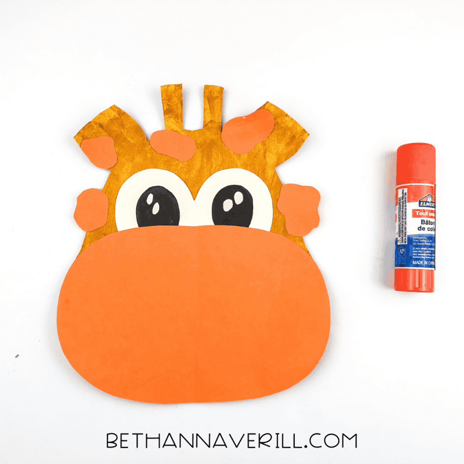 Orange spots glued onto the giraffe’s head and ears, surrounding the eyes.