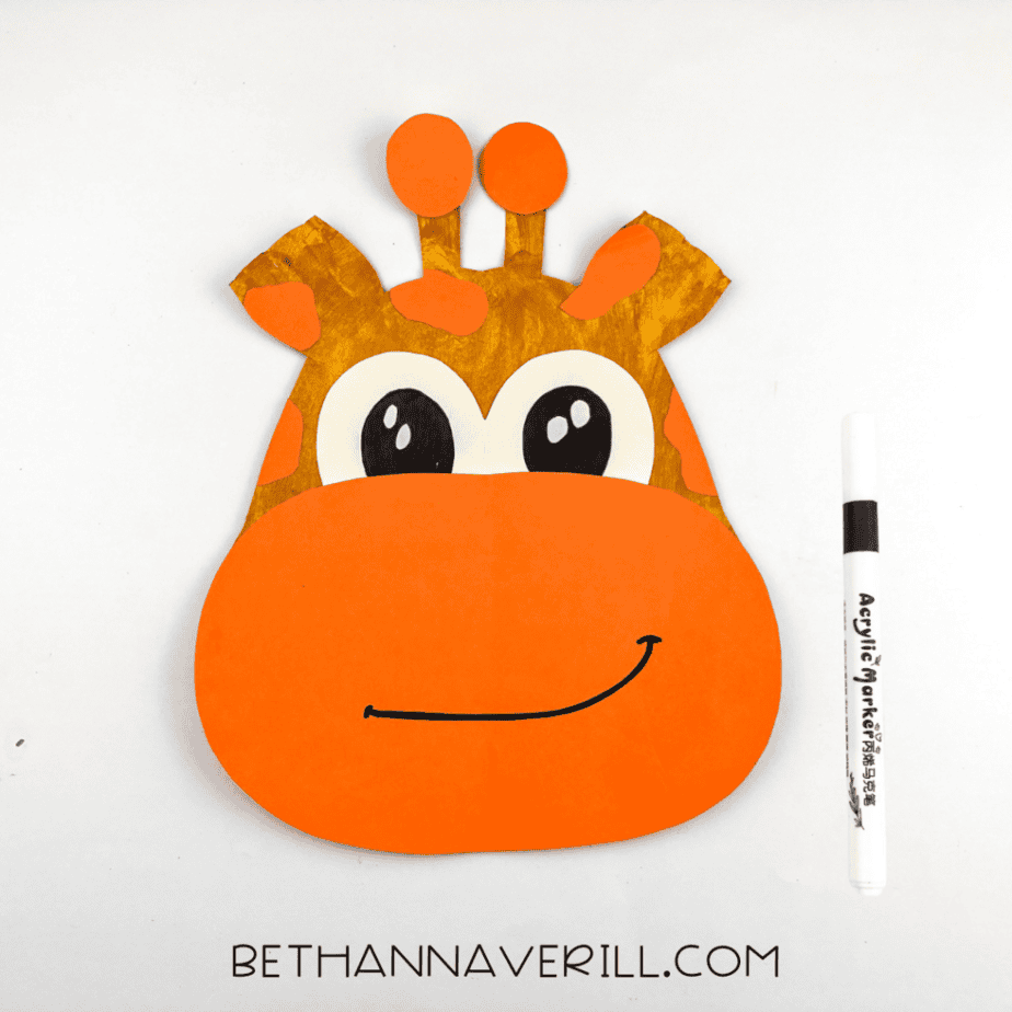 A black smile drawn onto the giraffe’s orange muzzle using a marker.