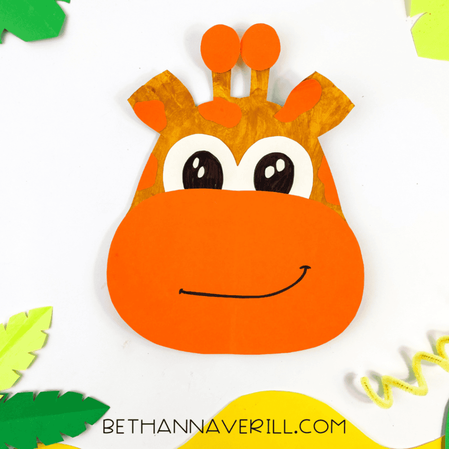 Completed giraffe paper plate craft with surrounding jungle-themed decorations like leaves and vines.