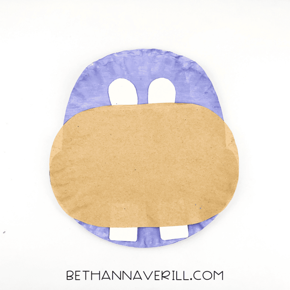 Two white eyes glued above the muzzle on the purple paper plate.