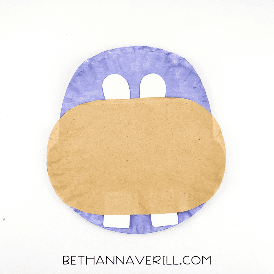 Two white eyes glued above the muzzle on the purple paper plate.