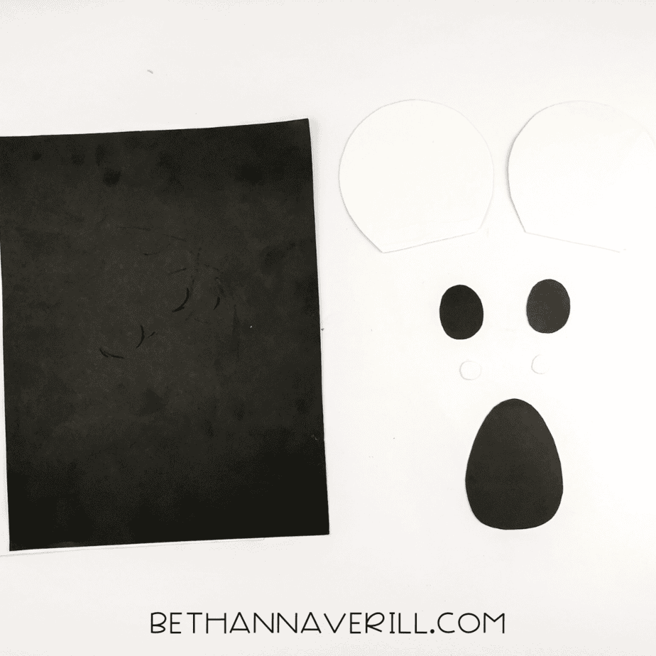 Black and white construction paper cut into koala facial features: ears, eyes, eye highlights, and a nose.