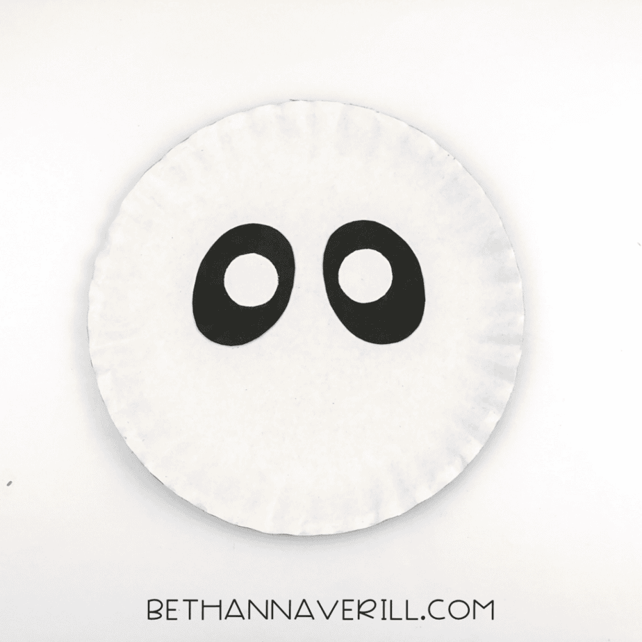 The eye patches and eyes now glued onto a white paper plate as the beginning of the panda’s face.