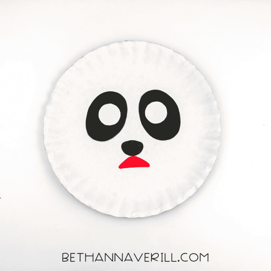 A black nose and red mouth glued beneath the eyes on the paper plate.