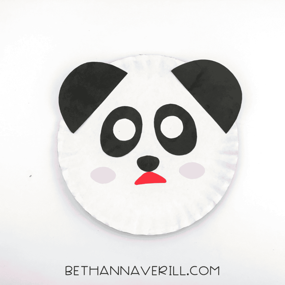 Large black half circles glued to the top edge of the paper plate as ears.