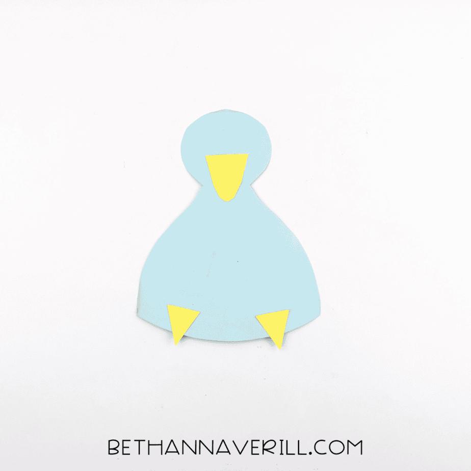 A blue paper body with yellow feet and a yellow beak glued into place.