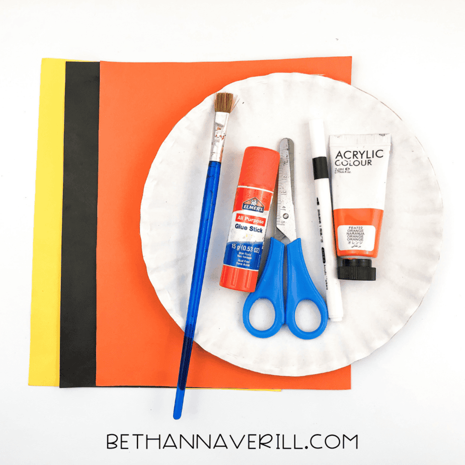 A plate with a paper plate, scissors, paint, and glue.