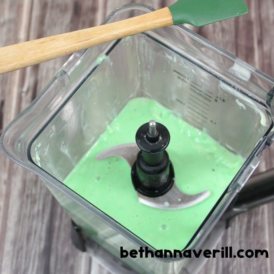 Blender filled with bright green Nickelodeon slime mixture after adding food coloring and blending ingredients.
