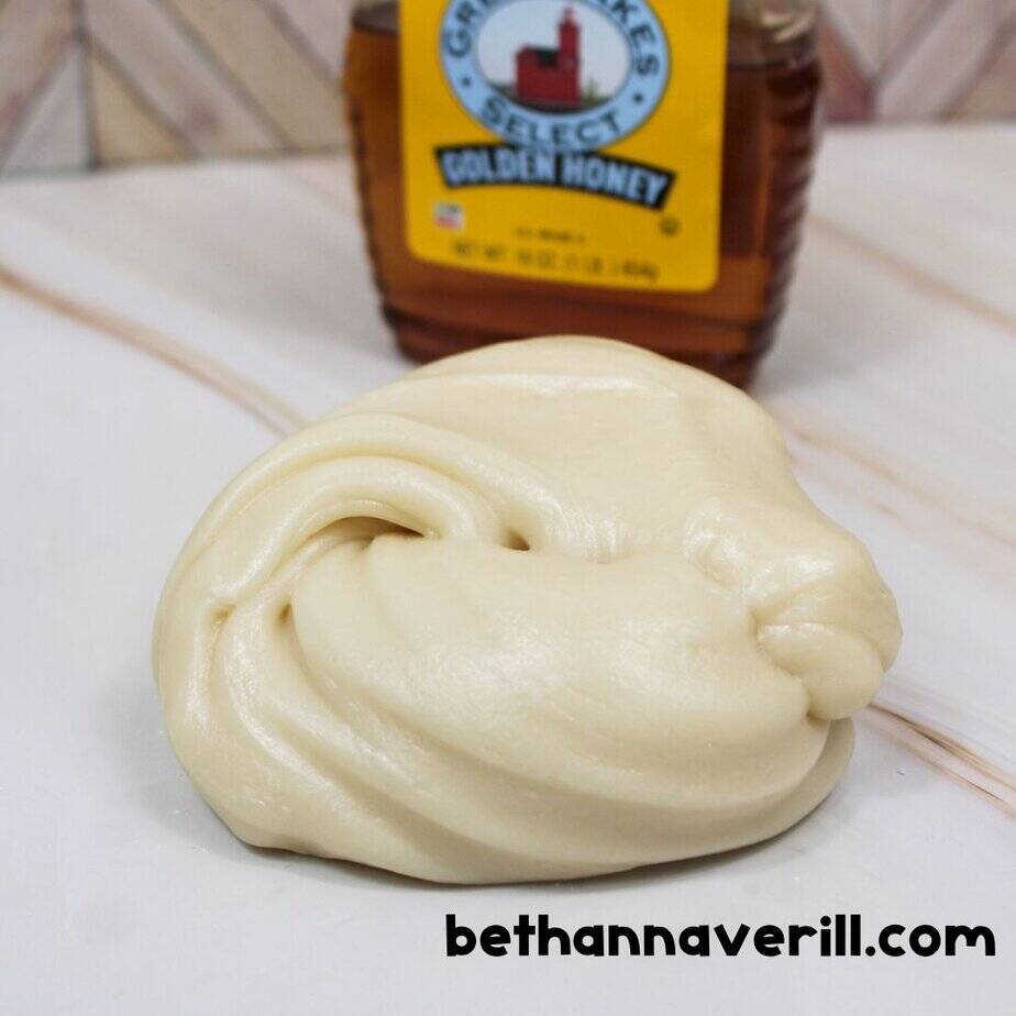 Smooth, creamy ball of honey slime sitting in front of a bottle of Golden Honey labeled "Great Lakes Select," with the website bethannaverill.com in the corner.