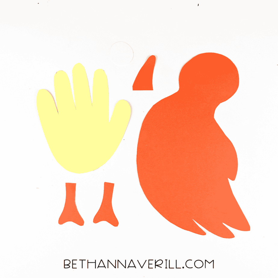 All paper pieces cut out – bird body, beak, feet, handprint wing, and eye.