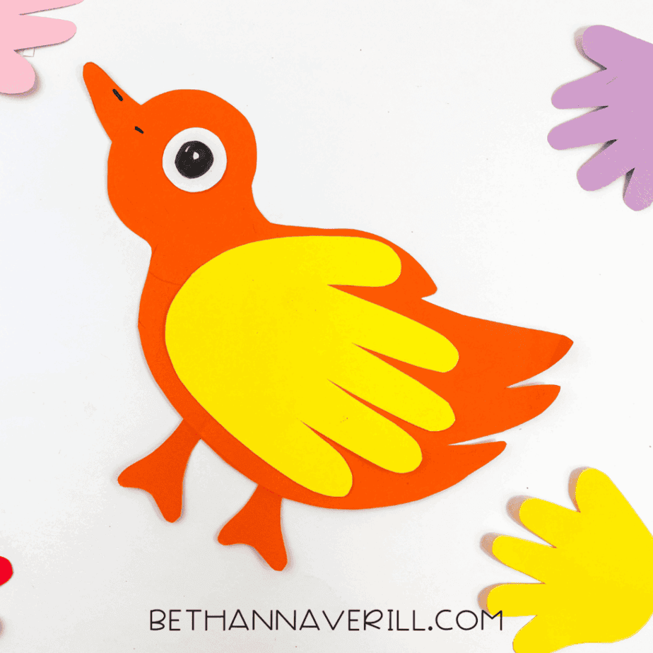 Colorful final bird handprint craft surrounded by extra handprint cutouts.