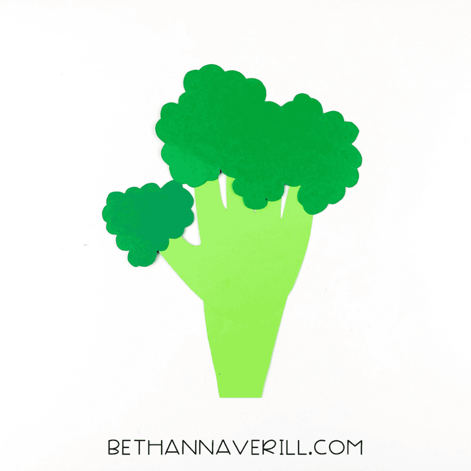 Green handprint shape glued to a broccoli stalk base with cut-out florets laid nearby.