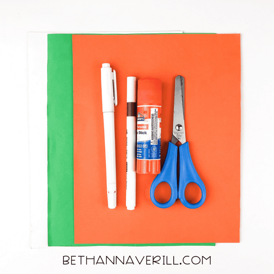 Materials for carrot craft: construction paper, glue stick, scissors, black and white markers