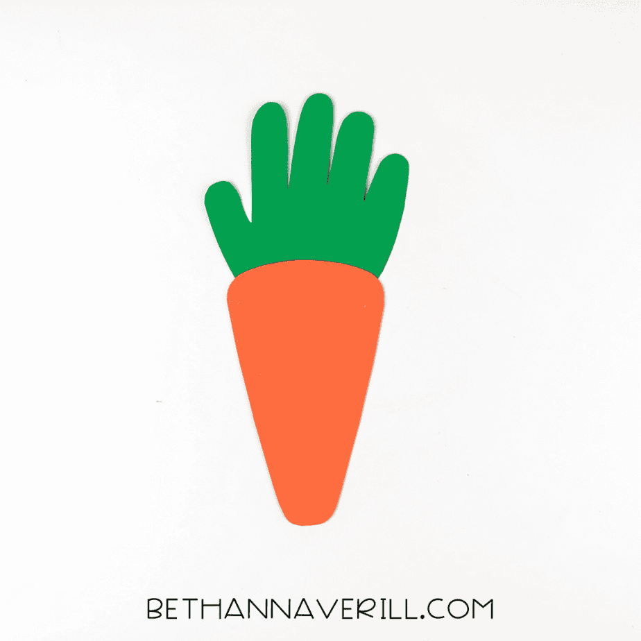Green handprint glued behind orange carrot shape to form the top
